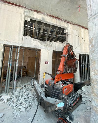En oransje rivningsrobot i arbeid på en byggeplass under innendørs sanering.