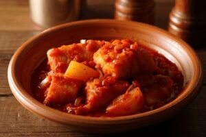 Rød bacalao med tomatsaus, poteter og chili i en leirskål